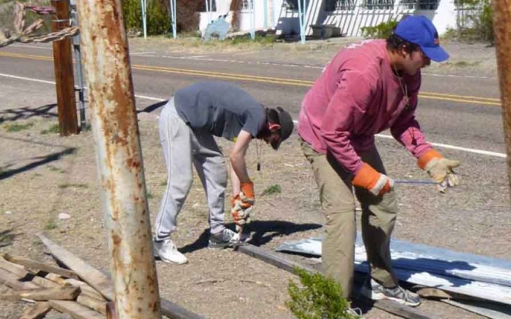 two students wearing gloves participate in a service project with outward bound